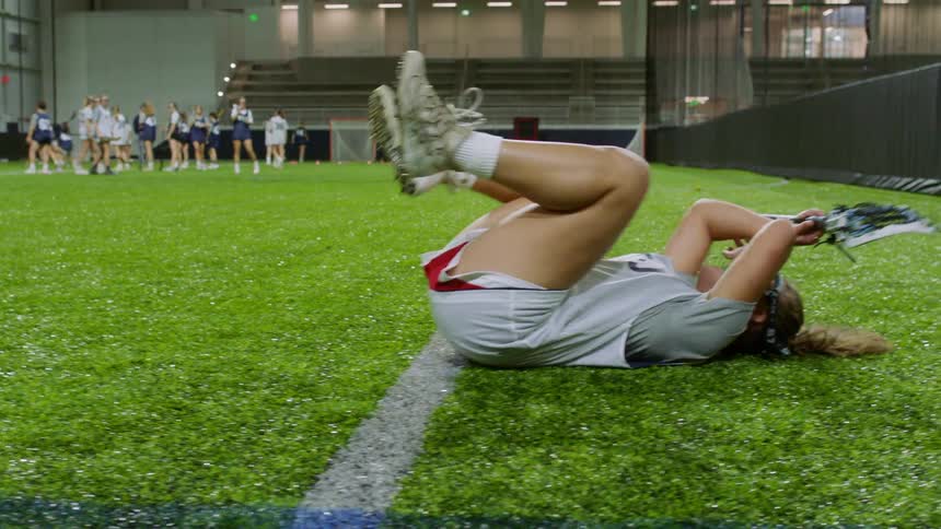 A teenage girl plays lacrosse in an indoor arena