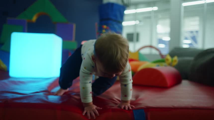 An infant crawls on an indoor play space with foam blocks