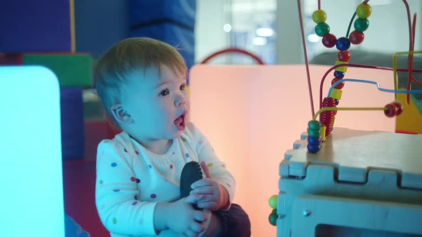 A baby sitting next to a toy playing with a slipper