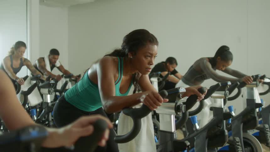 A group of people ride power bikes in a gym class