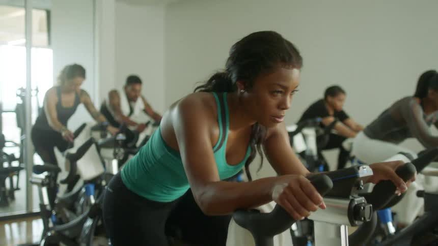 Fit woman wearing sports clothes exercises in a static bicycle on a gym