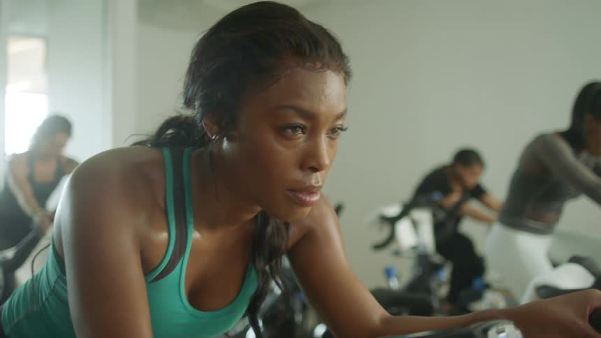 People exercise in gym on stationary bicycles