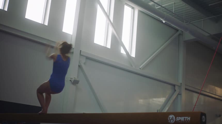Woman does back flip on balance beam