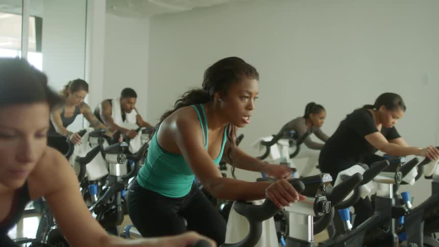 A group of people ride powered bicycles in a gym class