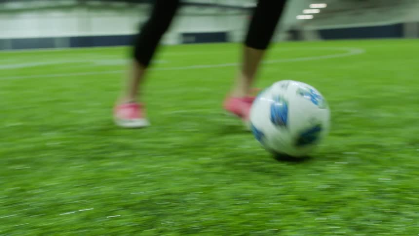 Woman playing soccer on the artificial grass of a soccer field