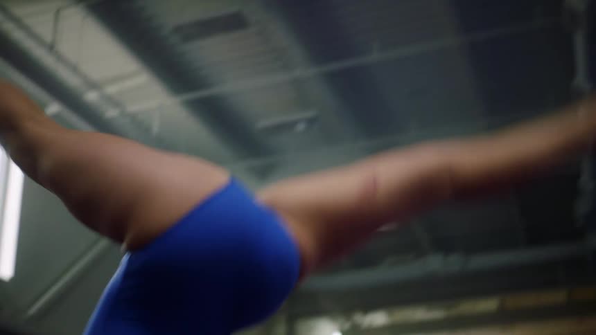 A teenage girl does a back flip in a gym