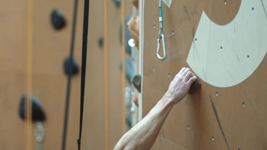 Young bald bearded man climbs an indoor climbing wall