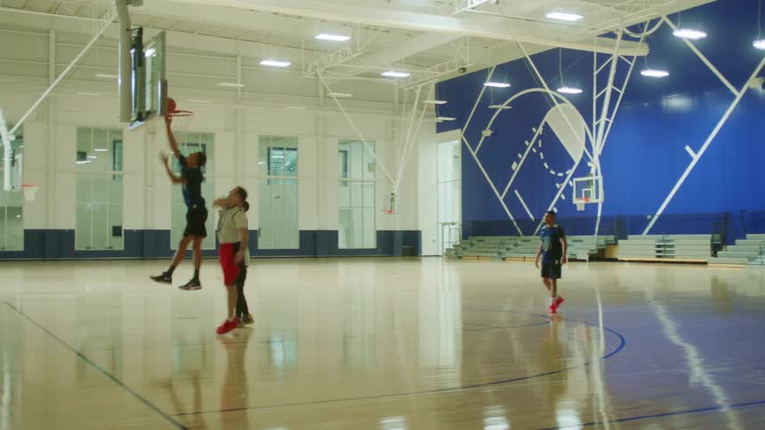 A group of males play indoor basketball