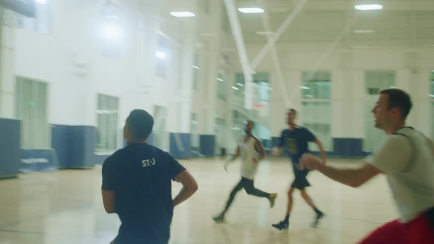 Men playing basketball in gymnasium