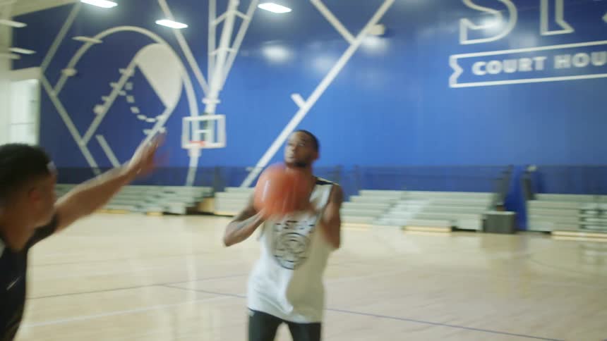 Men playing basketball in gymnasium
