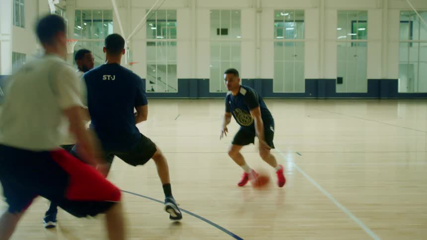 A group of males play indoor basketball