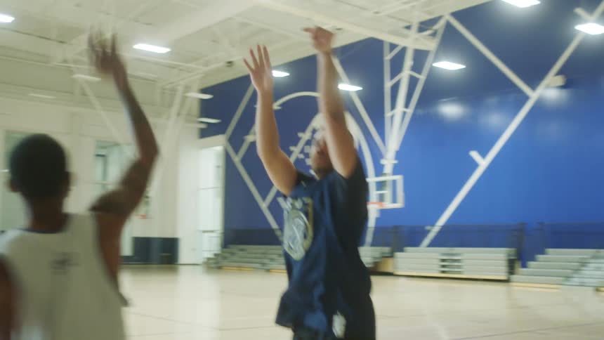 A group of men play basketball at an indoor court