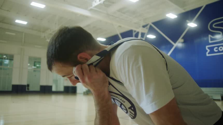 Player swipes the sweat on his forehead waiting for a play in the indoors basketball court