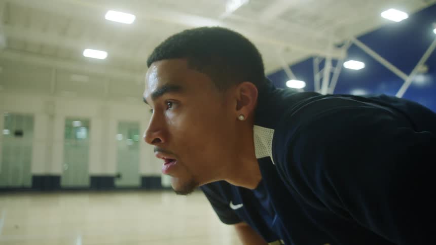 A young black man concentrating on a basketball court