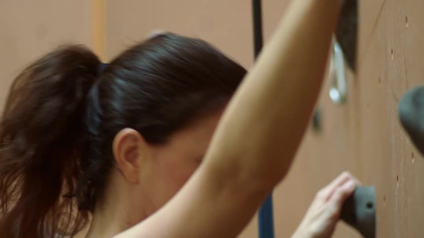 A woman rock climbing at an indoor climbing wall