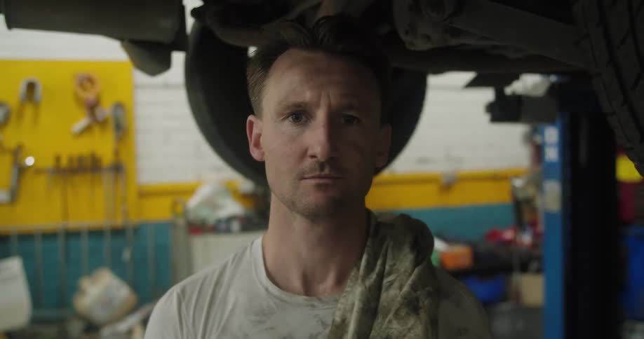 Mechanic stands underneath vehicle in garage