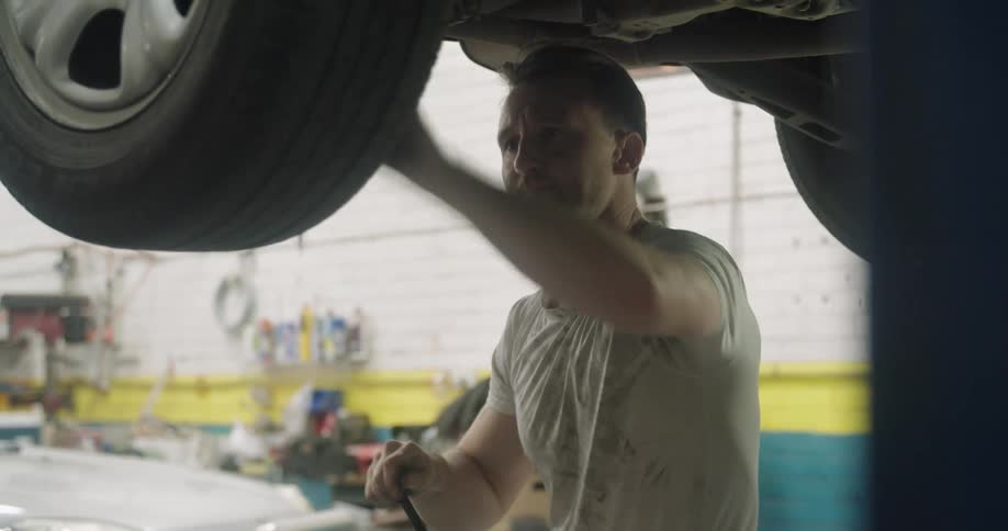 A mechanic tightens a bolt on a tire on a car
