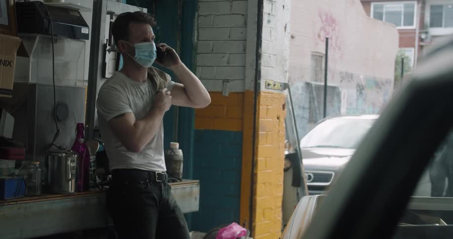 A man in a medical mask speaks on a mobile phone