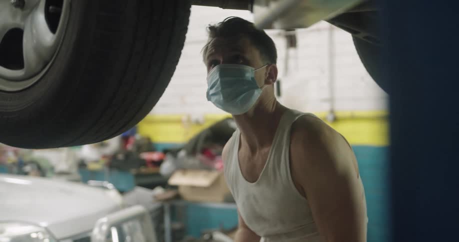 A mechanic uses a tool to tighten something on a vehicle