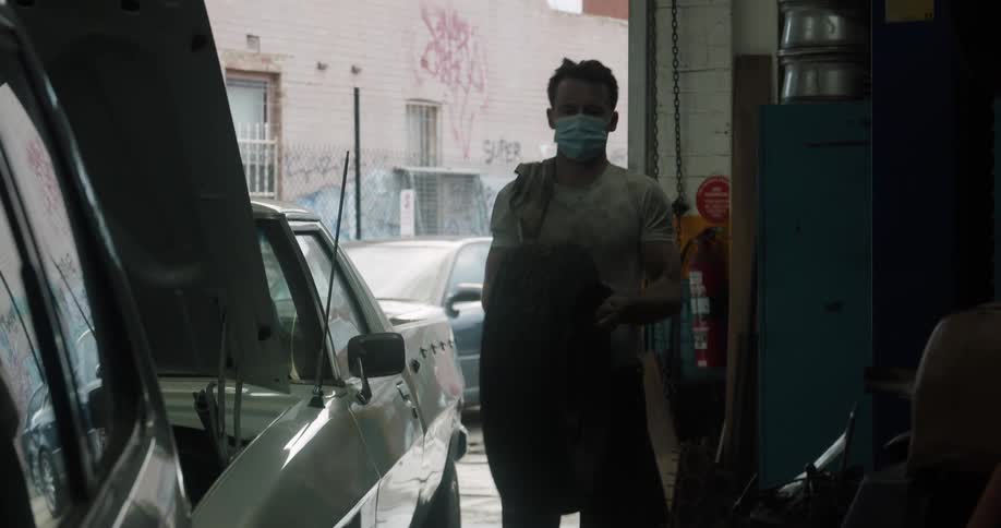 A mechanic carries a tire in to a shop