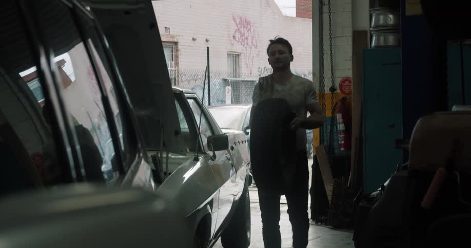 A mechanic carries a tire inside the garage