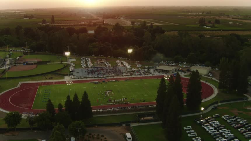A football field with players playing football surrounded by trees