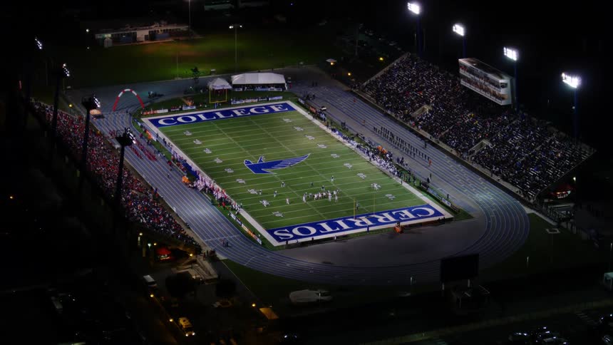 Aerial view of a crowd watching a football match in an outdoors stadium at night