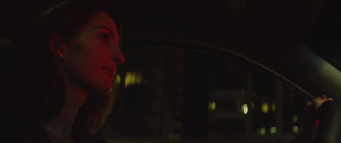 Side view of a woman driving a car at night
