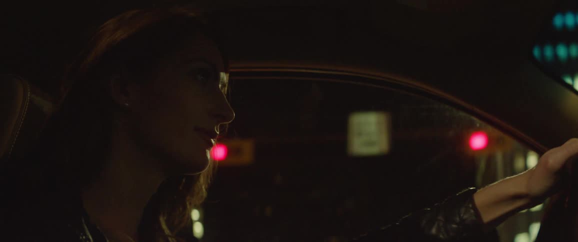 A woman driving her car in a city at night