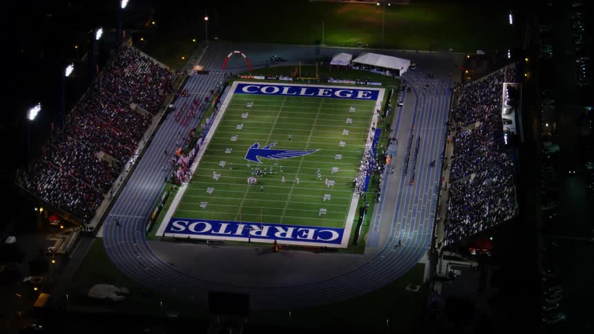 A stadium filled with people in bleachers watching a football game