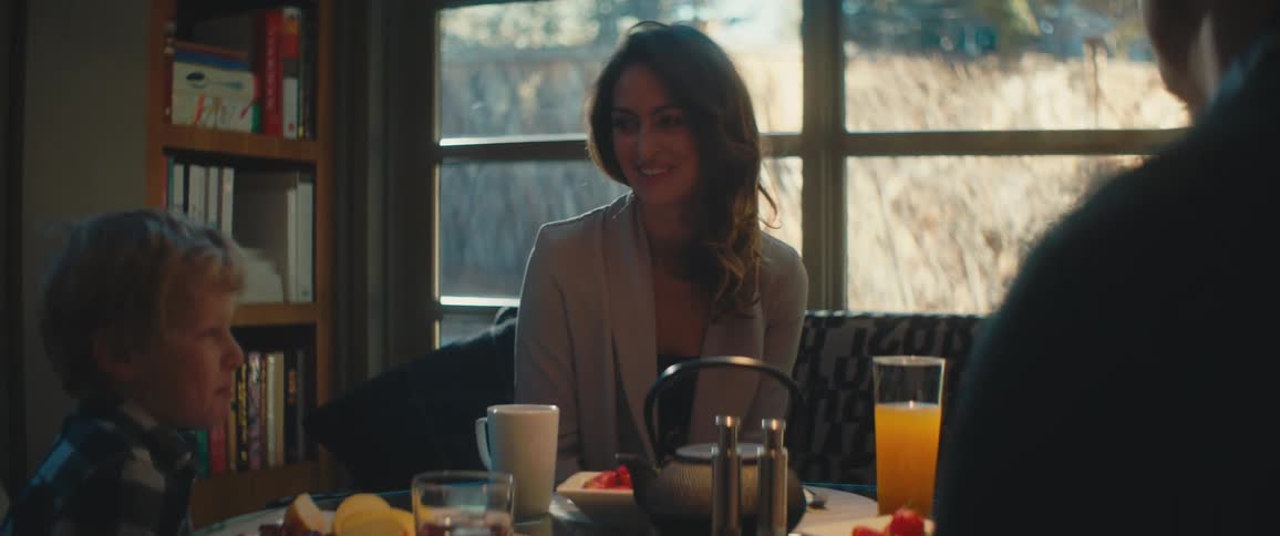 A family sits together around a dining table with food and drink