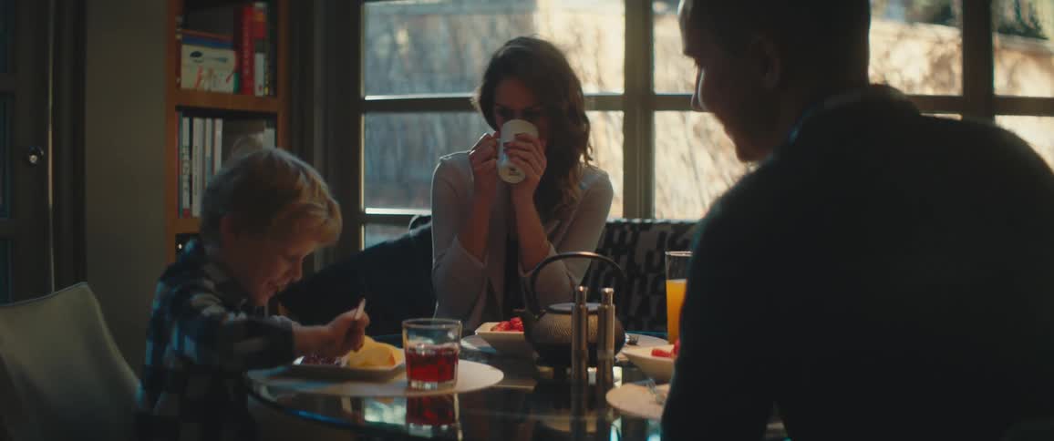 A family sits around a home table together with food and drink