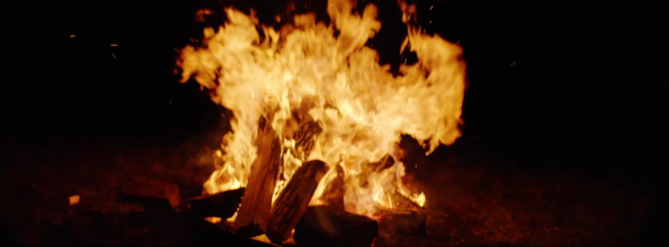 A fire is burning outdoors at night