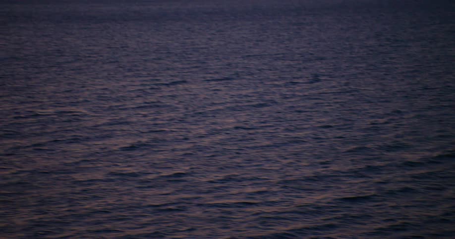 Aerial view of a sea surface with red sky on the horizon at dusk