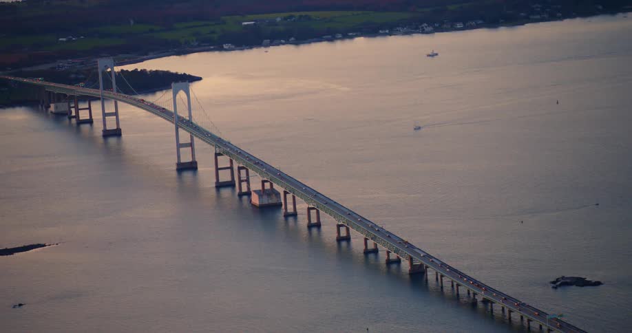 An aerial view of boats in a lake and cars driving across a bridge