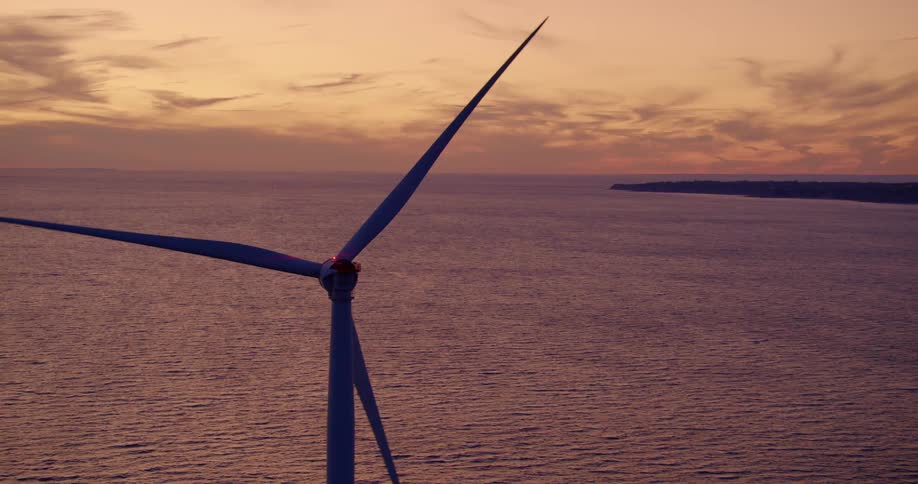 Aerial view of wind turbine in the sea off the coast at sunset