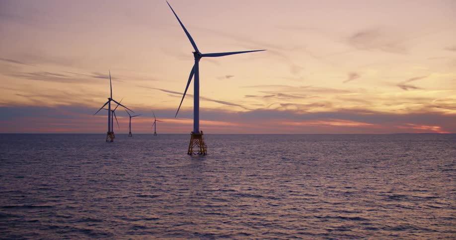 Wind turbines in open ocean at sunrise