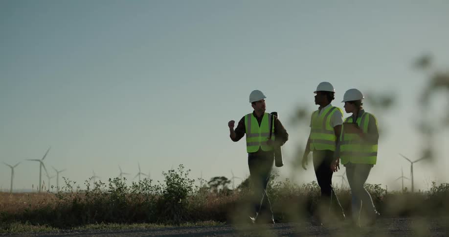 Three construction workers are walking in a rural area