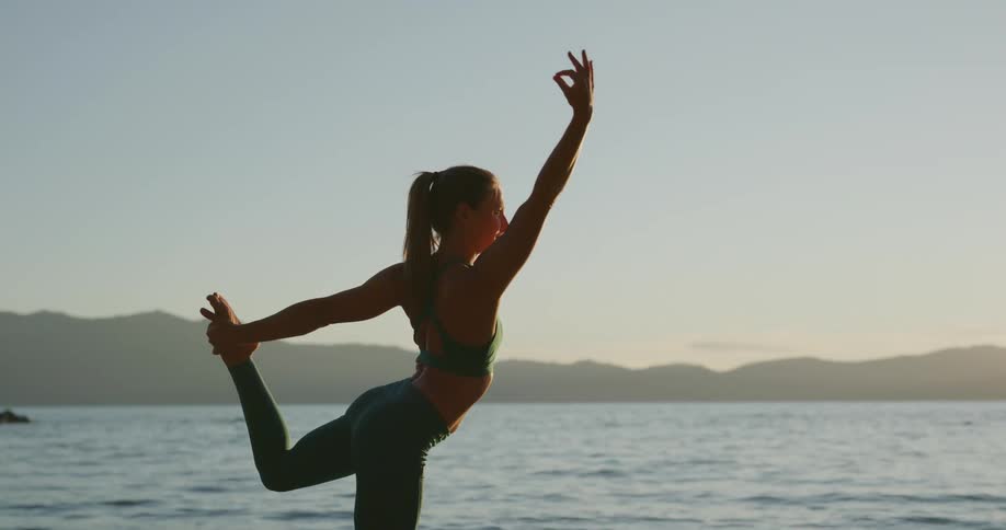 A woman is stretching outdoors by the ocean
