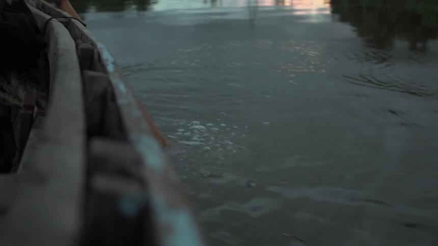 A small wooden boat is being moved with an ore