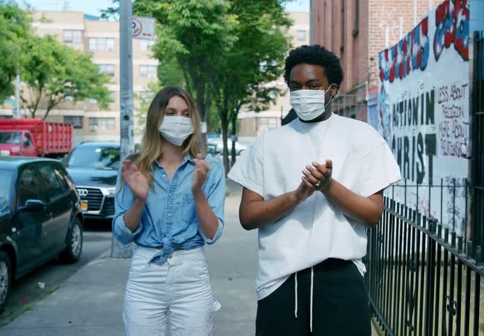 A man and woman are outdoors in a city clapping