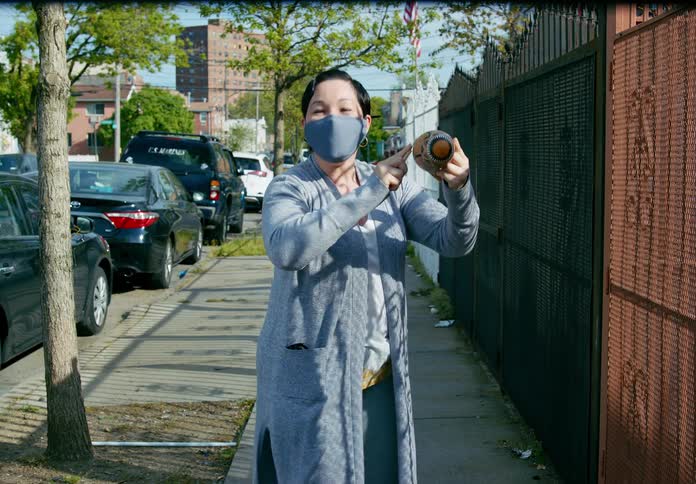A woman with a mask playing an instrument with vehicles and buildings in the background