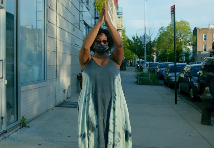 A woman is standing outdoors and clapping her hands