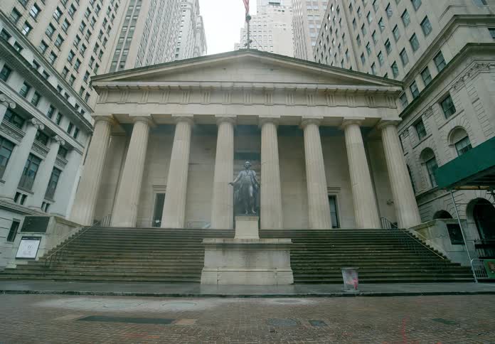 Steam blows by a classical building with a statue in the front