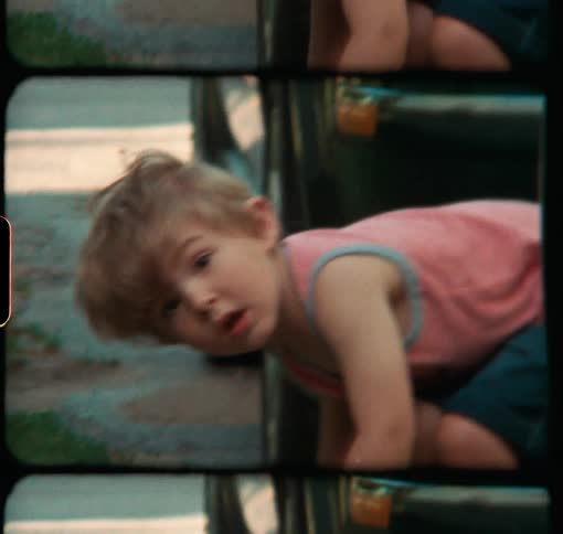 A little boy plays with toy trucks in the driveway during the summer