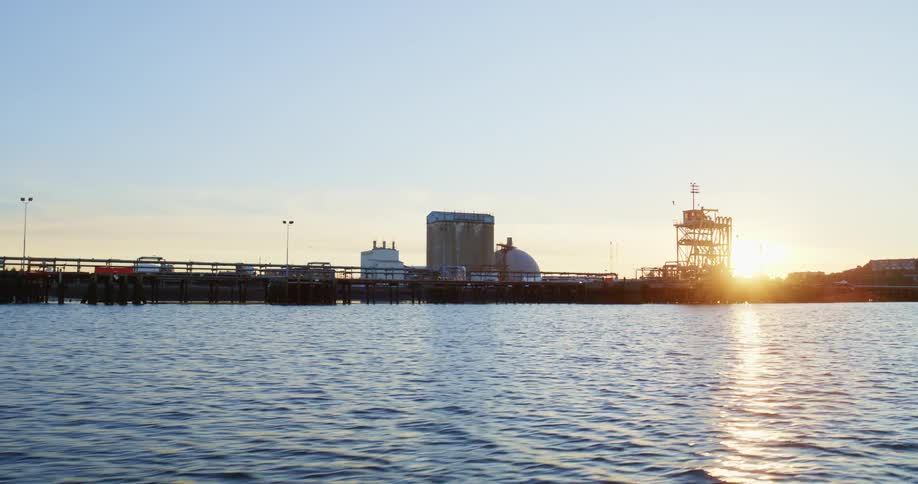 A series of buildings are lining the coastline next to a long pier