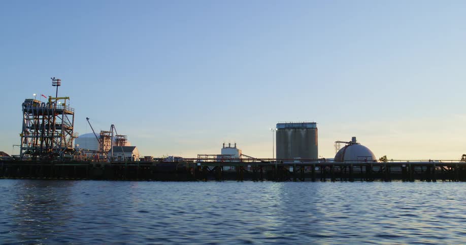 Silos in a port near the ocean at sunset
