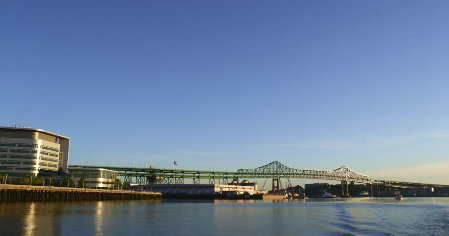 A bridge extends from the coast towards a landmass in the distance