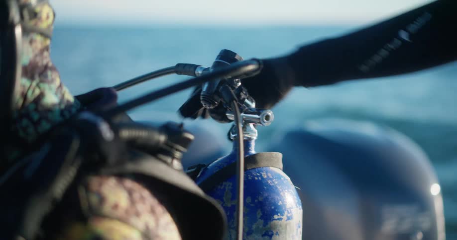 A diver adjusts another divers tank on a boat