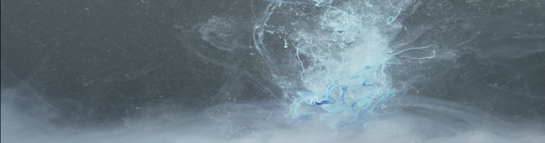 Colorful liquid blue ink sink moving in waves and patterns on a diffusing haze